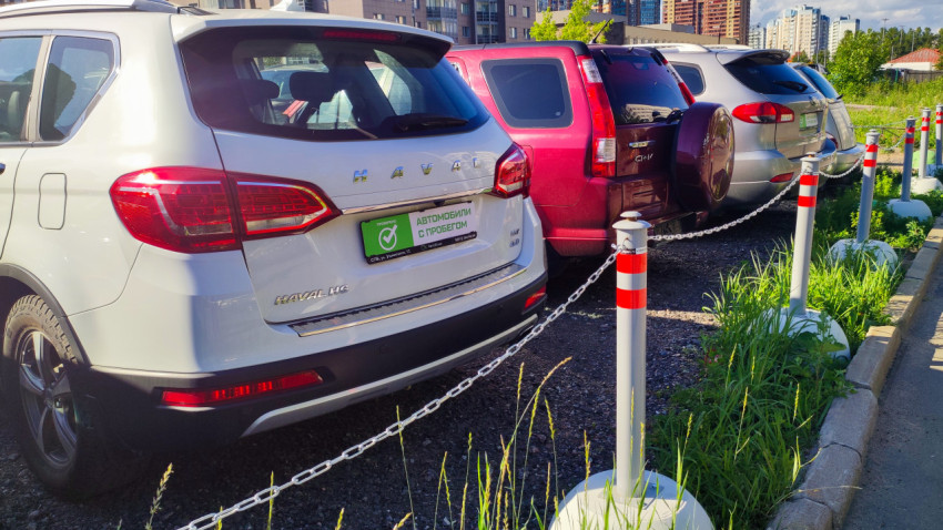 Линия припаркованных автомобилей за цепным ограждением на гравийной площадке