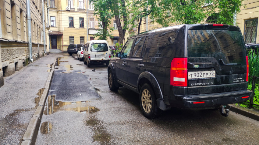 Land Rover Discovery 3 во дворе после дождя на мокром асфальте с лужами