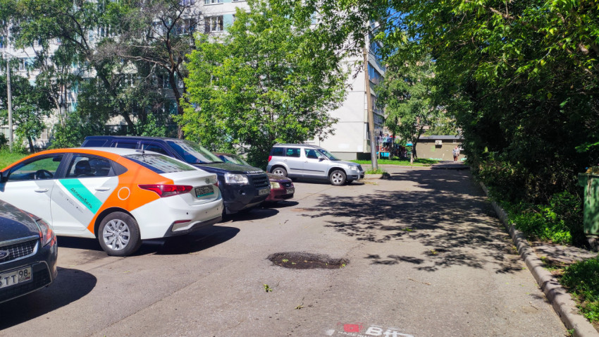 Дворовой проезд с припаркованными машинами и автомобилем каршеринга Делимобиль