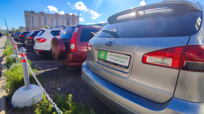 Ряд припаркованных автомобилей на стоянке и задняя часть Subaru с табличкой «автомобили с пробегом»