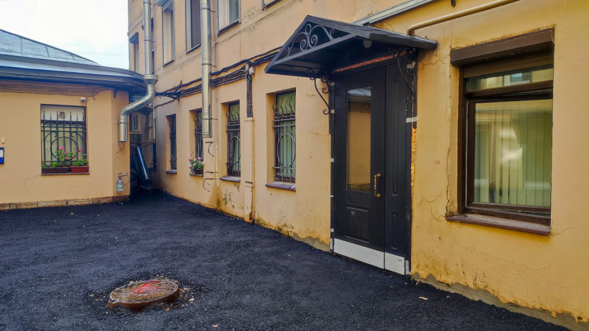 Входная группа с кованым козырьком и новым асфальтом во внутреннем дворе жилого дома