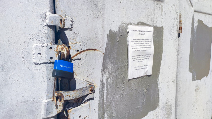 Ржавый запор гаражных ворот с навесным замком FALLADIUM и объявлением о работах