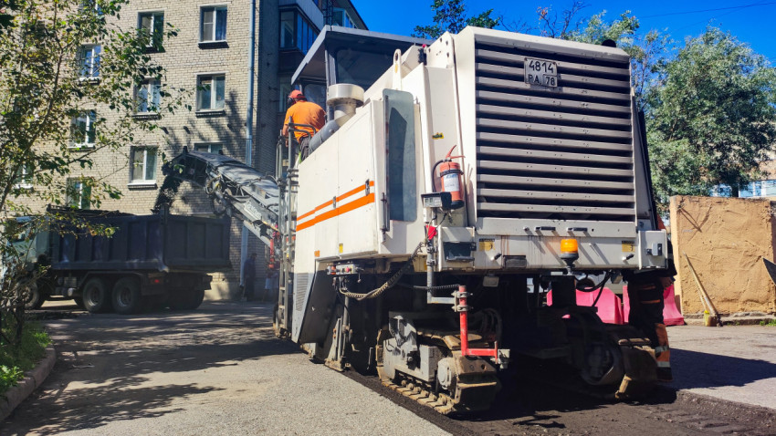 Крупный план дорожной фрезы и конвейера, загружающего асфальтовую крошку в самосвал во дворе