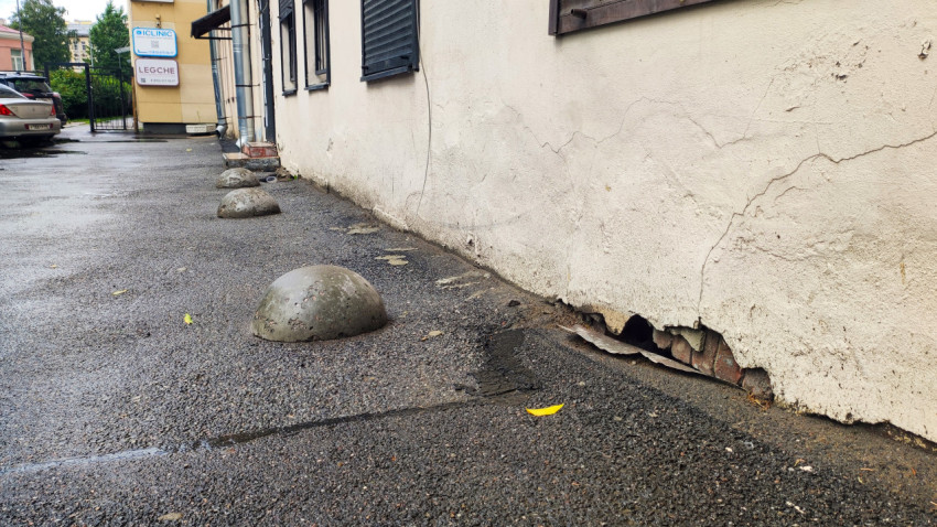 Повреждённая штукатурка цоколя и бетонные полусферы-ограничители вдоль стены