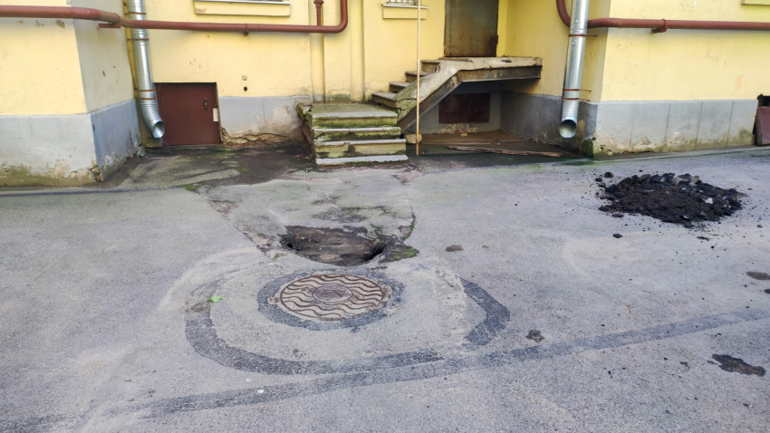 Люк и выбоина в асфальте у входа в подвальное помещение жилого дома