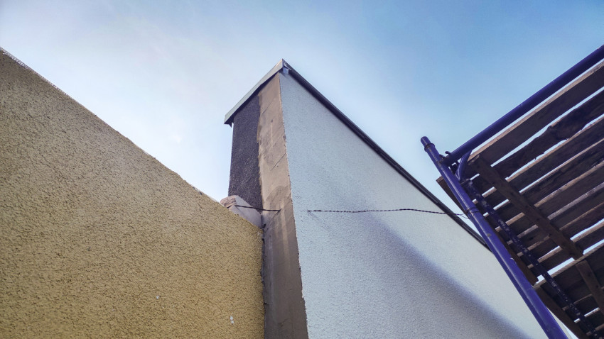 Узел примыкания фасада и кровли на углу здания с защитной планкой и лесами