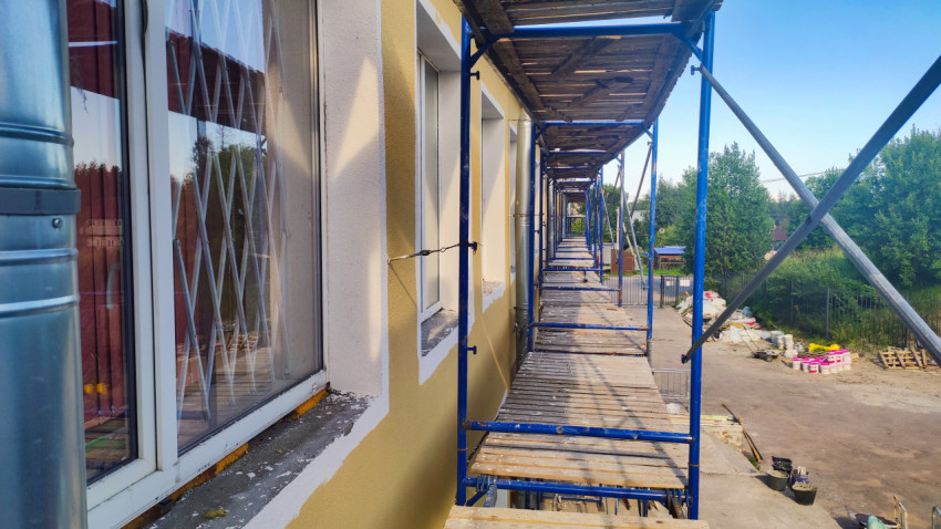 Длинный проход по строительным лесам вдоль фасада с окнами во время ремонта