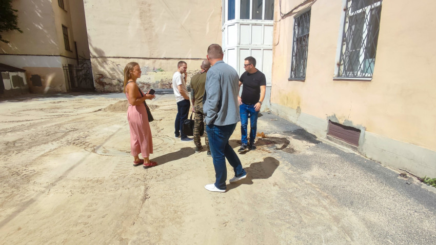 Обсуждение работ во дворе рядом со стеной здания и песчаным основанием