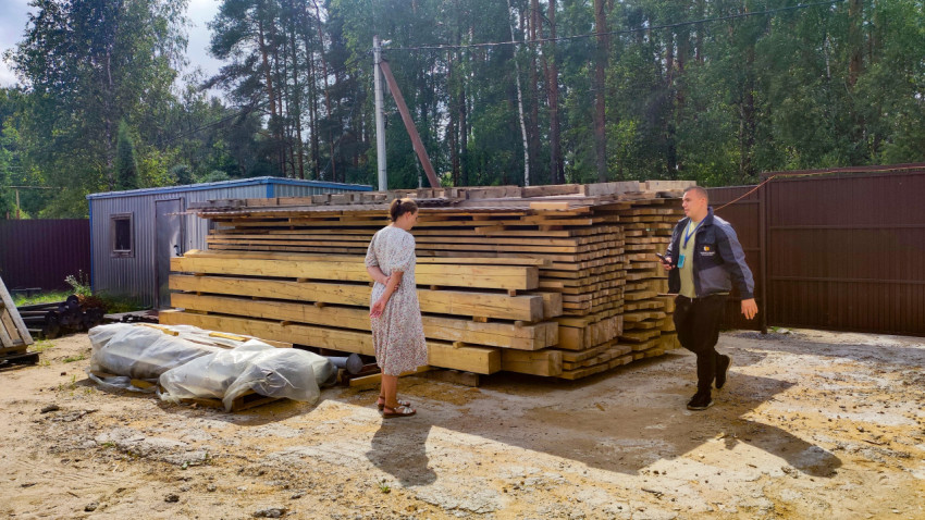 Осмотр штабеля пиломатериалов на строительной площадке у забора и бытовки