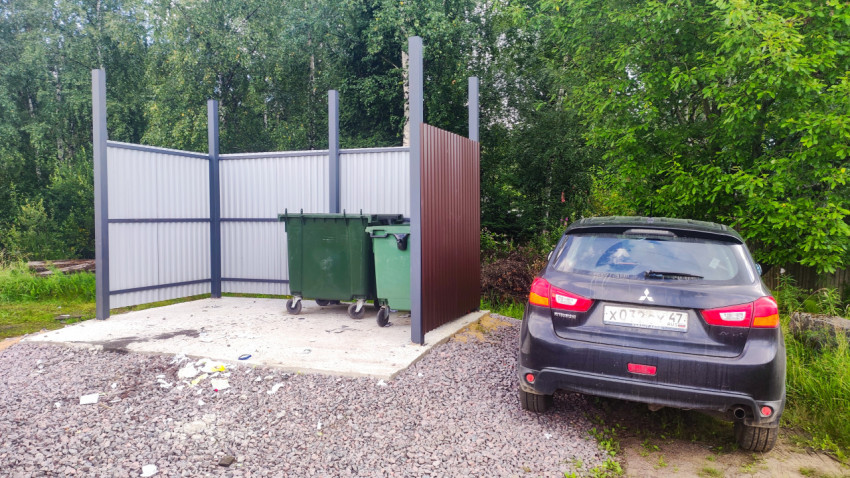 Мусорная площадка с зелеными контейнерами для отходов в ограждении из профлиста