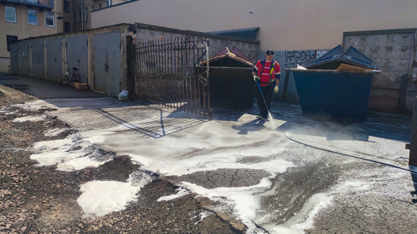 Мойка дворового покрытия шлангом с пеной у контейнеров и металлических ворот