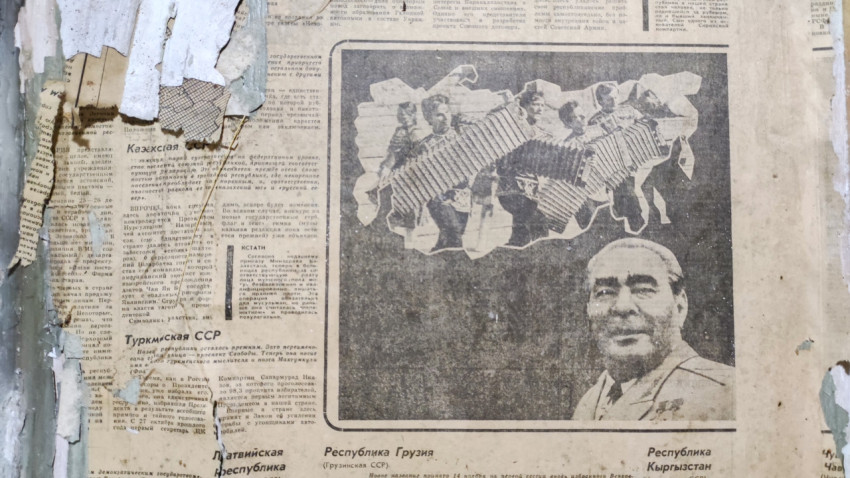 Газетные обои с портретом и оборванными слоями краски создают жёсткую «гранж» фактуру на стене