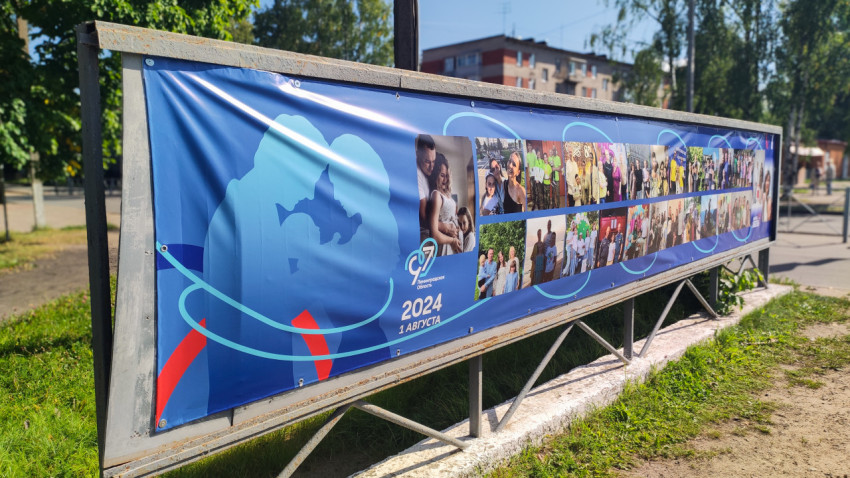 Длинный уличный билборд с синим баннером и фотоколлажем на металлической раме у дороги