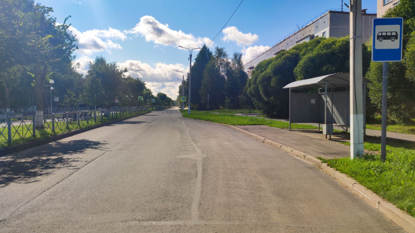 Остановка общественного транспорта на городской улице рядом с тротуаром и ограждением
