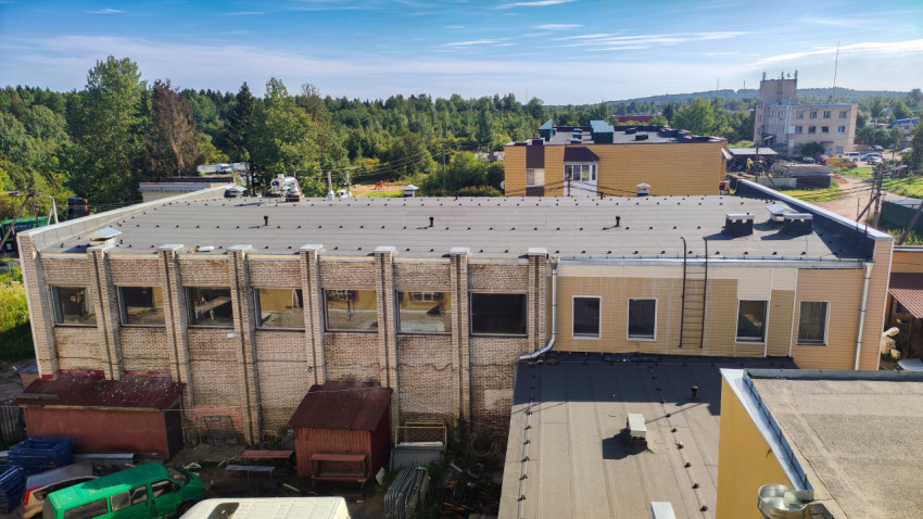 Крыша промышленного корпуса с вентиляционными выходами и обзором пригородной застройки