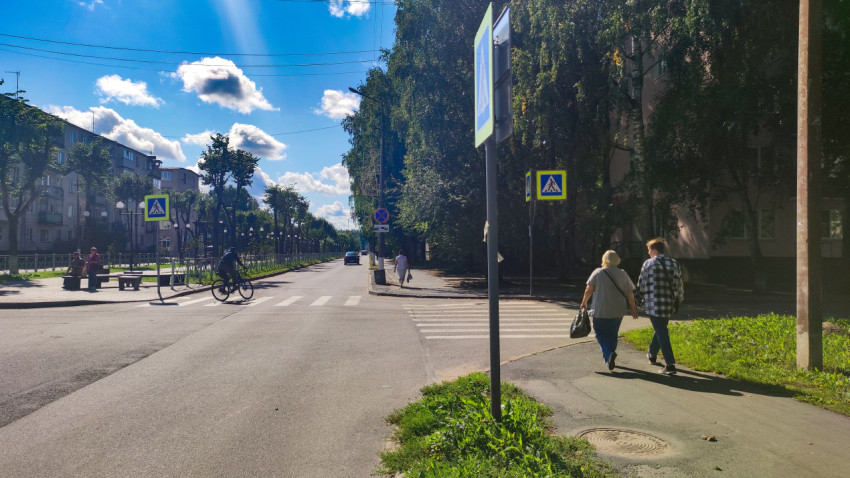 Пешеходный переход на городской улице с дорожными знаками, велосипедистом и прохожими