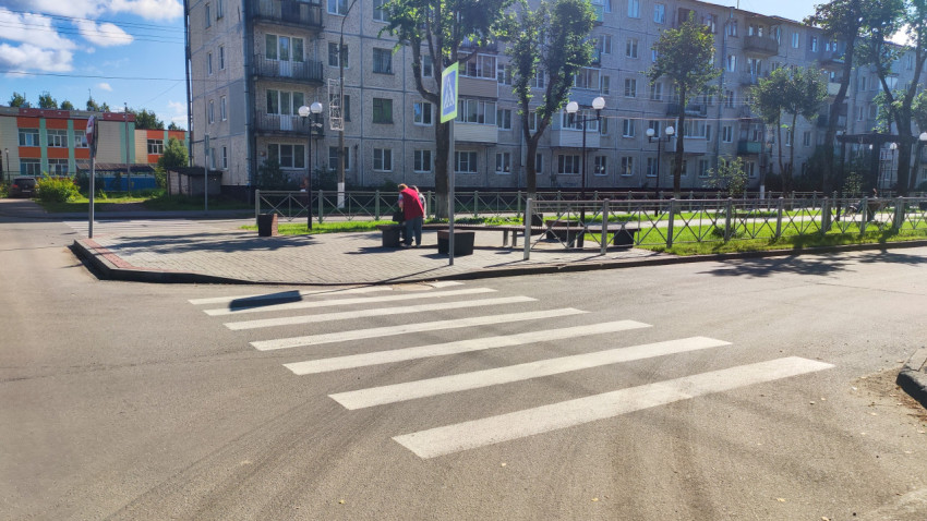 Пешеходный переход со знаком и зеброй на улице у жилого дома и зелёной зоны