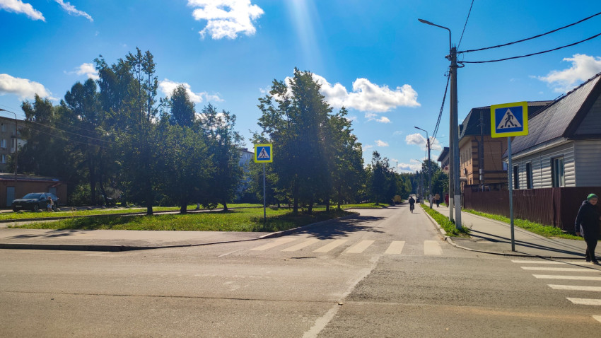 Пешеходный переход с дорожными знаками на улице частного сектора