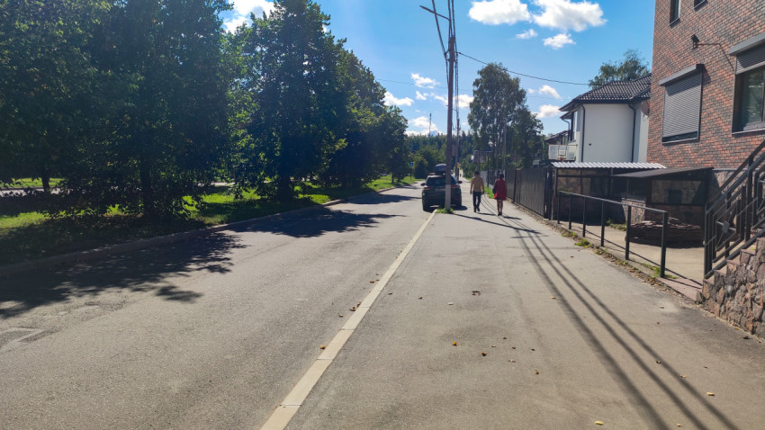 Кирпичный жилой дом с входной группой и тротуаром вдоль улицы в солнечную погоду
