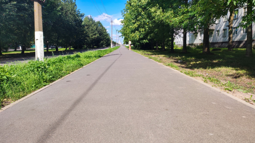 Дорожка вдоль деревьев и жилого дома, уходящая далеко вперёд