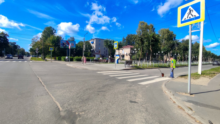 Рабочий с измерительным колесом у пешеходного перехода на городской улице