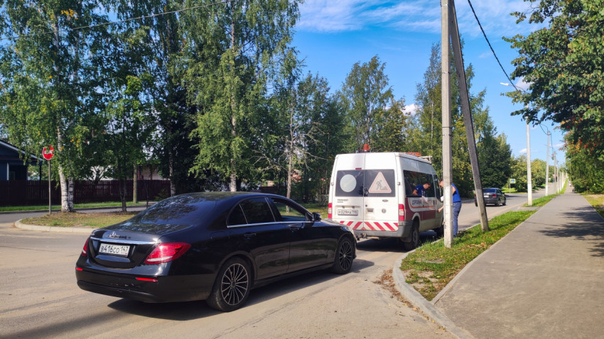 Чёрный седан Mercedes-Benz у служебного фургона дорожной лаборатории на городской улице