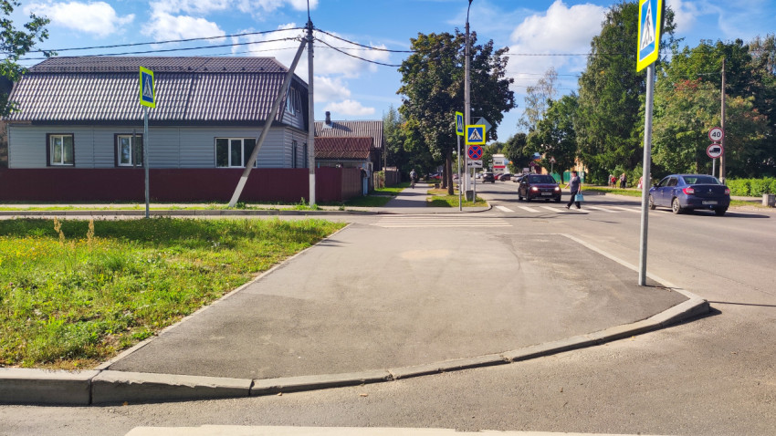 Пешеходный переход и дорожные знаки на улице рядом с частными домами