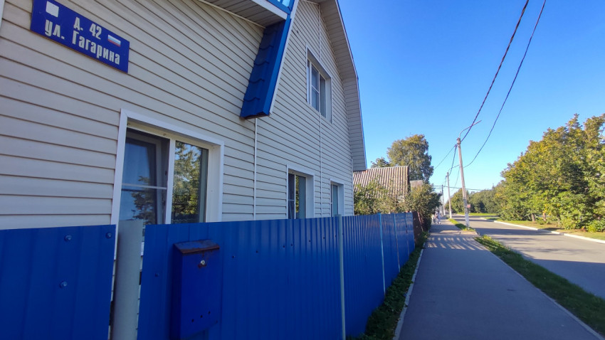 Адресная табличка «ул. Гагарина, д. 42» на фасаде рядом с забором
