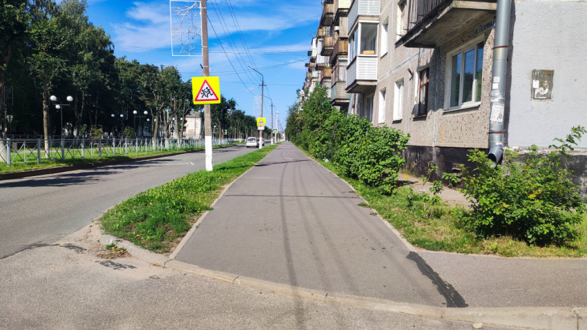 Тротуар вдоль многоэтажки и знак «Дети» на спокойной улице