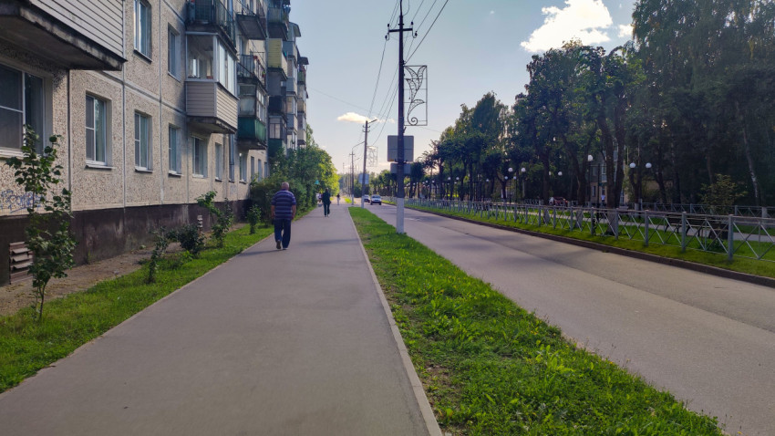 Тротуар вдоль пятиэтажек тянется параллельно дороге под проводами и фонарями