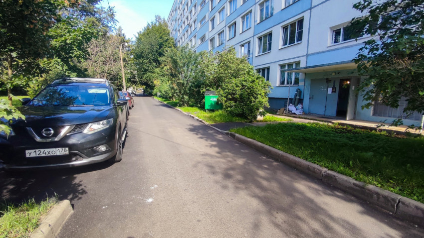 Дворовая проезжая часть с припаркованными автомобилями и фасадом жилого дома