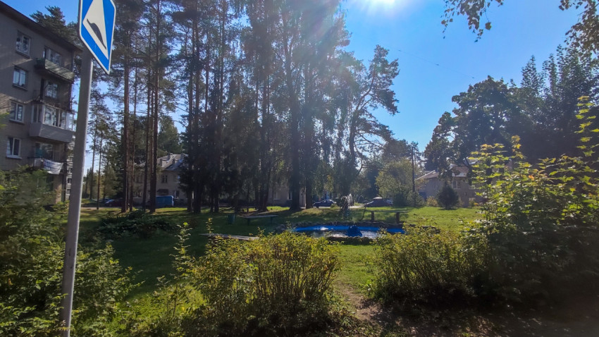 Дворовый фонтан с струёй воды и дорожным знаком на переднем плане