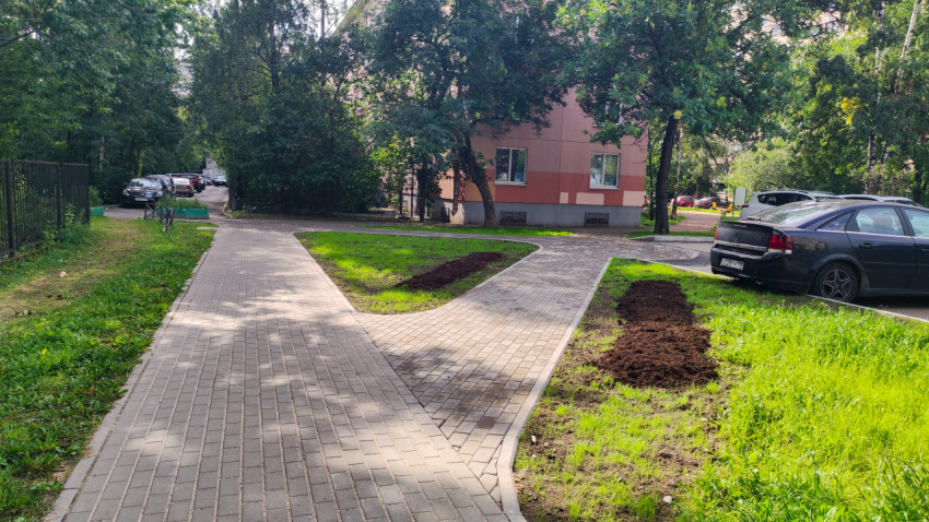 Тротуар вдоль двора с разрытым участком земли и припаркованными машинами
