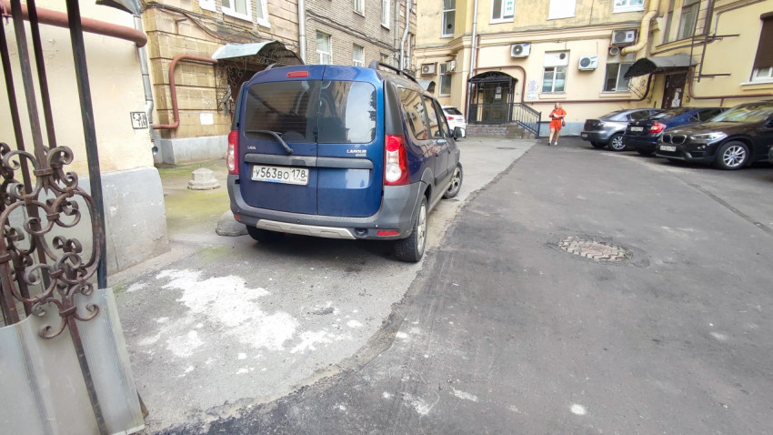 Синий универсал Lada Largus на дворовой парковке у подъезда и участка свежего асфальта с люком