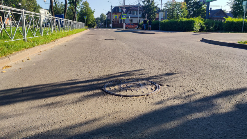 Чугунный люк на проезжей части перед пешеходным переходом и дорожными знаками