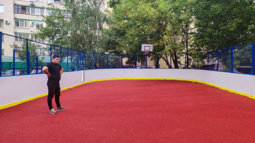 Мужчина на дворовой спортивной площадке с баскетбольным щитом