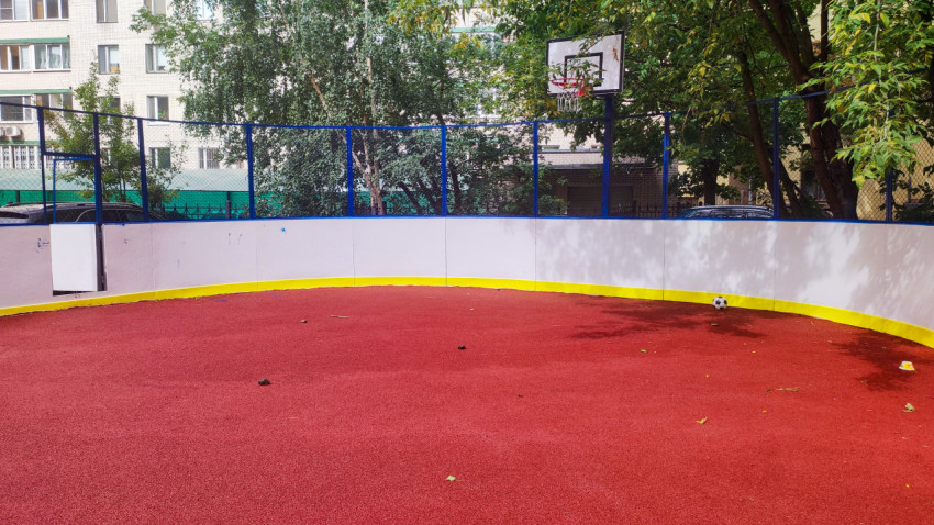 Угол дворовой площадки с баскетбольным щитом и футбольным мячом у борта