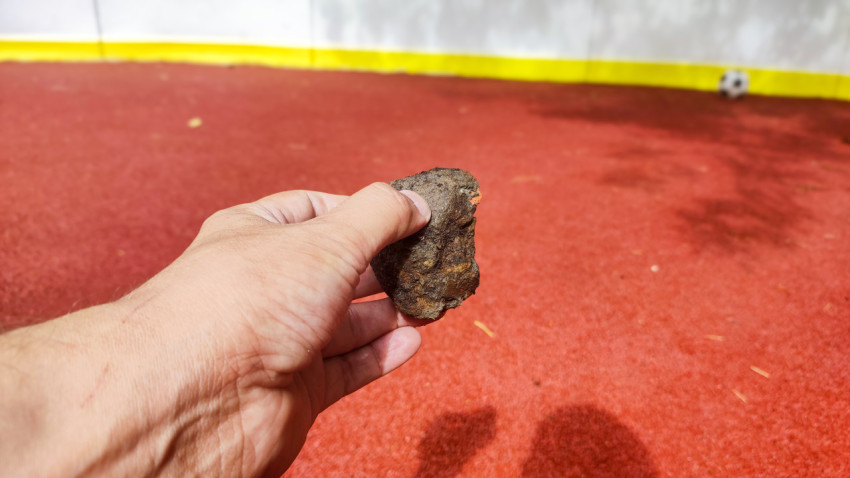 Крупный план руки с камнем на фоне уличной спортивной площадки