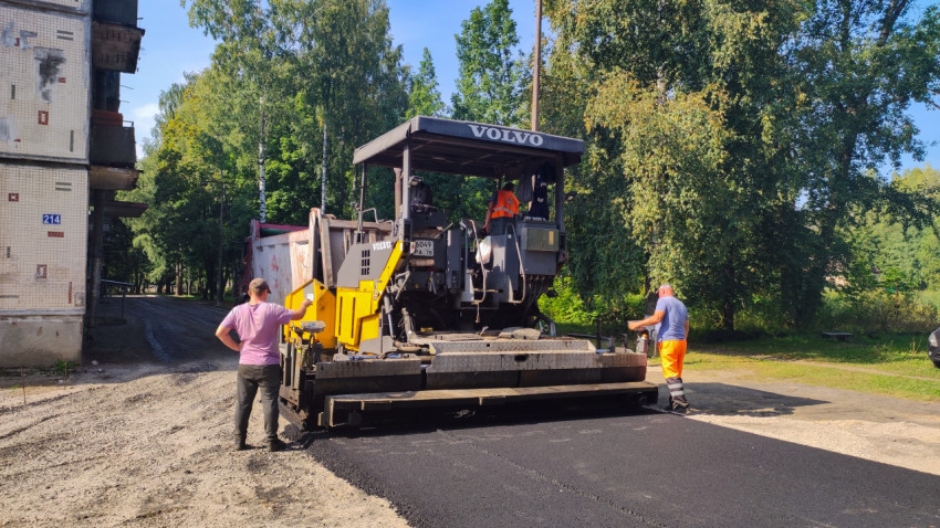 Асфальтоукладчик Volvo укладывает новый слой асфальта во дворе жилого дома