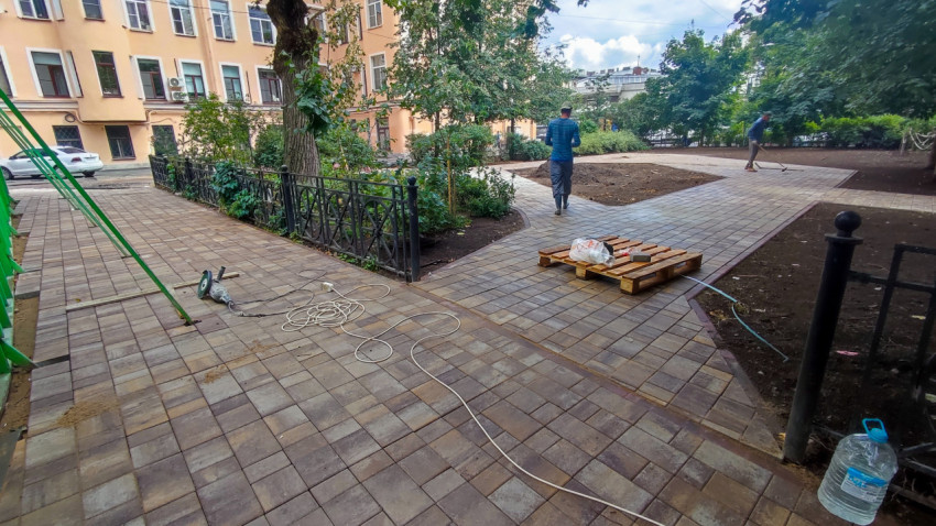 Укладка тротуарной плитки во дворе с паллетой и строительным инструментом