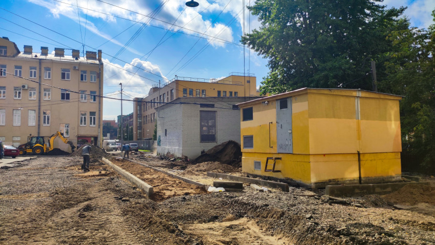 Земляные работы во дворе с экскаватором и траншеями перед укладкой коммуникаций