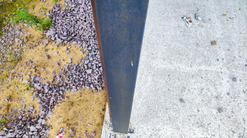 Основание металлического столба у бетонной площадки на гравийной отсыпке во дворе