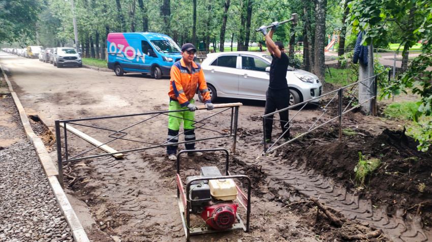 Монтаж столбов ограждения и уплотнение основания виброплитой на дворовой строительной площадке