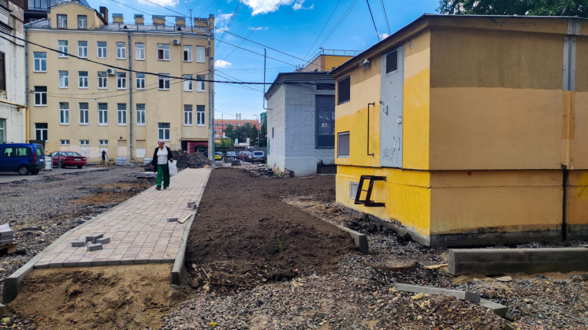 Укладка тротуарной плитки и бордюров во дворе рядом с хозяйственным строением