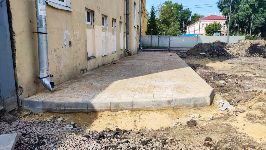 Укладка тротуарной плитки и бордюров вдоль жилого дома во дворе