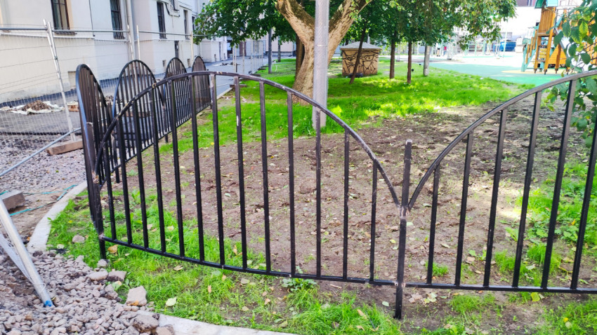 Низкое металлическое ограждение у газона на дворовой территории рядом с площадкой