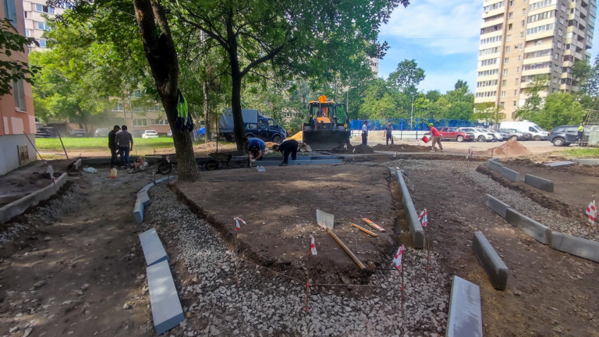 Работы по благоустройству двора с выставленными бордюрами, разметкой и техникой на подготовленном основании