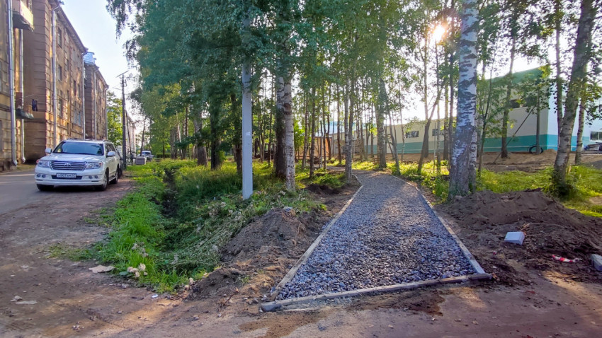 Протяжённый участок устройства тротуара с бордюрами и отсыпкой у здания в зелёной зоне