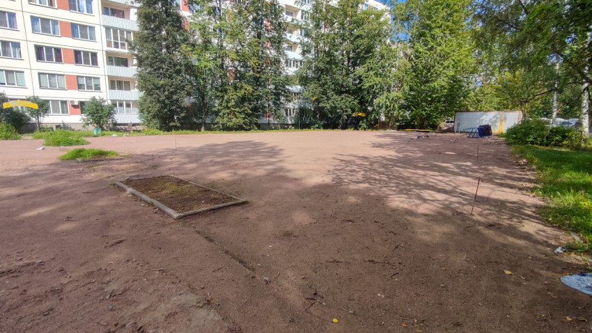 Расчищенный участок у жилого дома с колышками и бечёвкой размечен под дальнейшее благоустройство двора