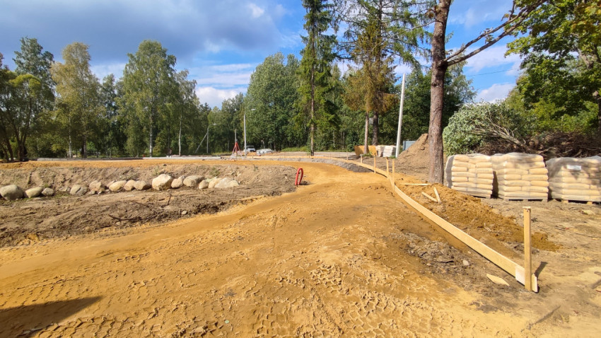 Подготовка основания пешеходной дорожки на стройплощадке среди деревьев